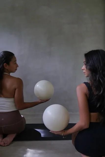 Two women seated with pilates barre balls at Feral Pilates Siargao