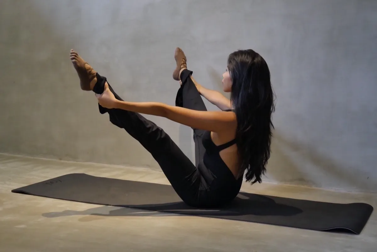Allegra De Borja demonstrating a V-sit with strap on the mat at Holding Space Siargao