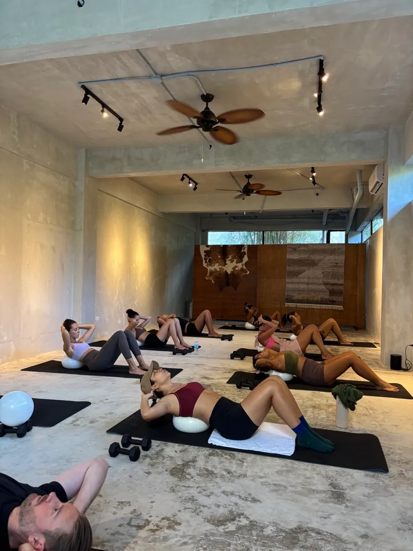 Group mat Pilates class doing crunches with barre balls at Feral Movement studio Siargao