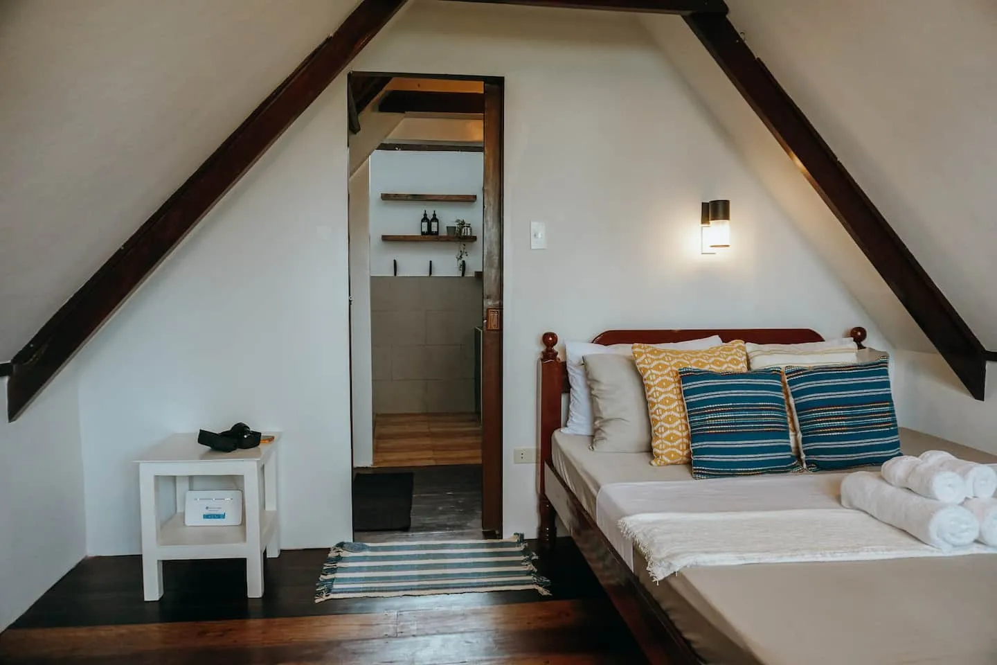 A bright bedroom under the peaked nipa roof with an ensuite doorway at Vultun House