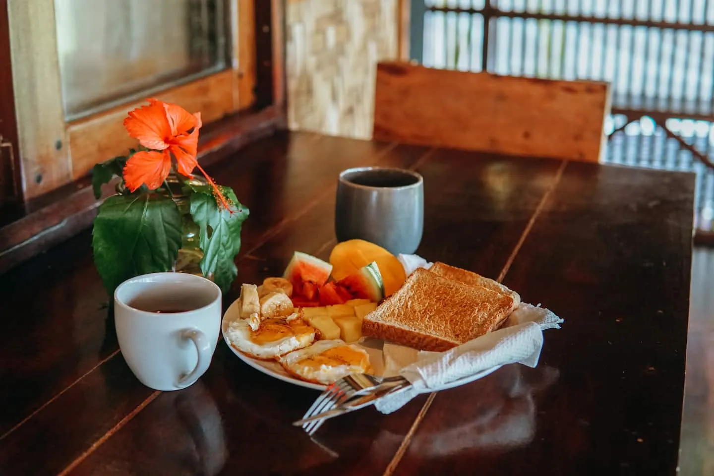A warm breakfast of coffee, toast, and fresh fruit set on the dark-wood table at Vultun House