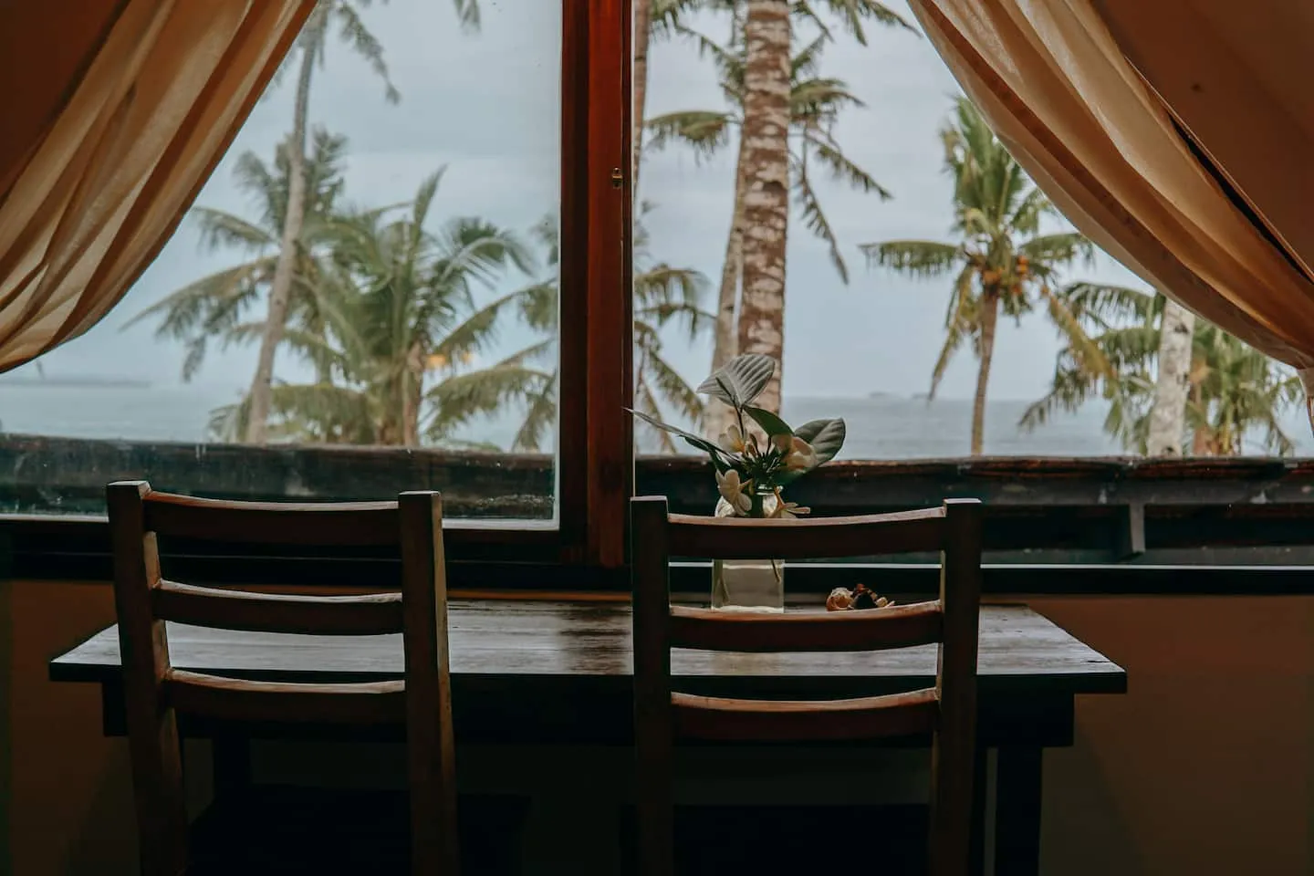 The dining table set by the window with palms and ocean views at Vultun House