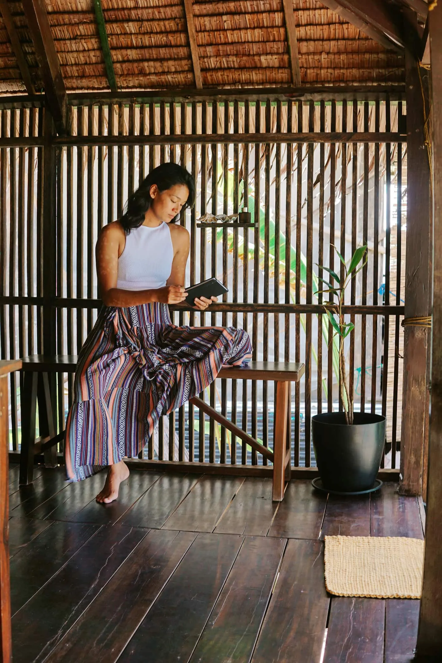 A guest resting on the open-air yoga deck framed by bamboo screens at Vultun House