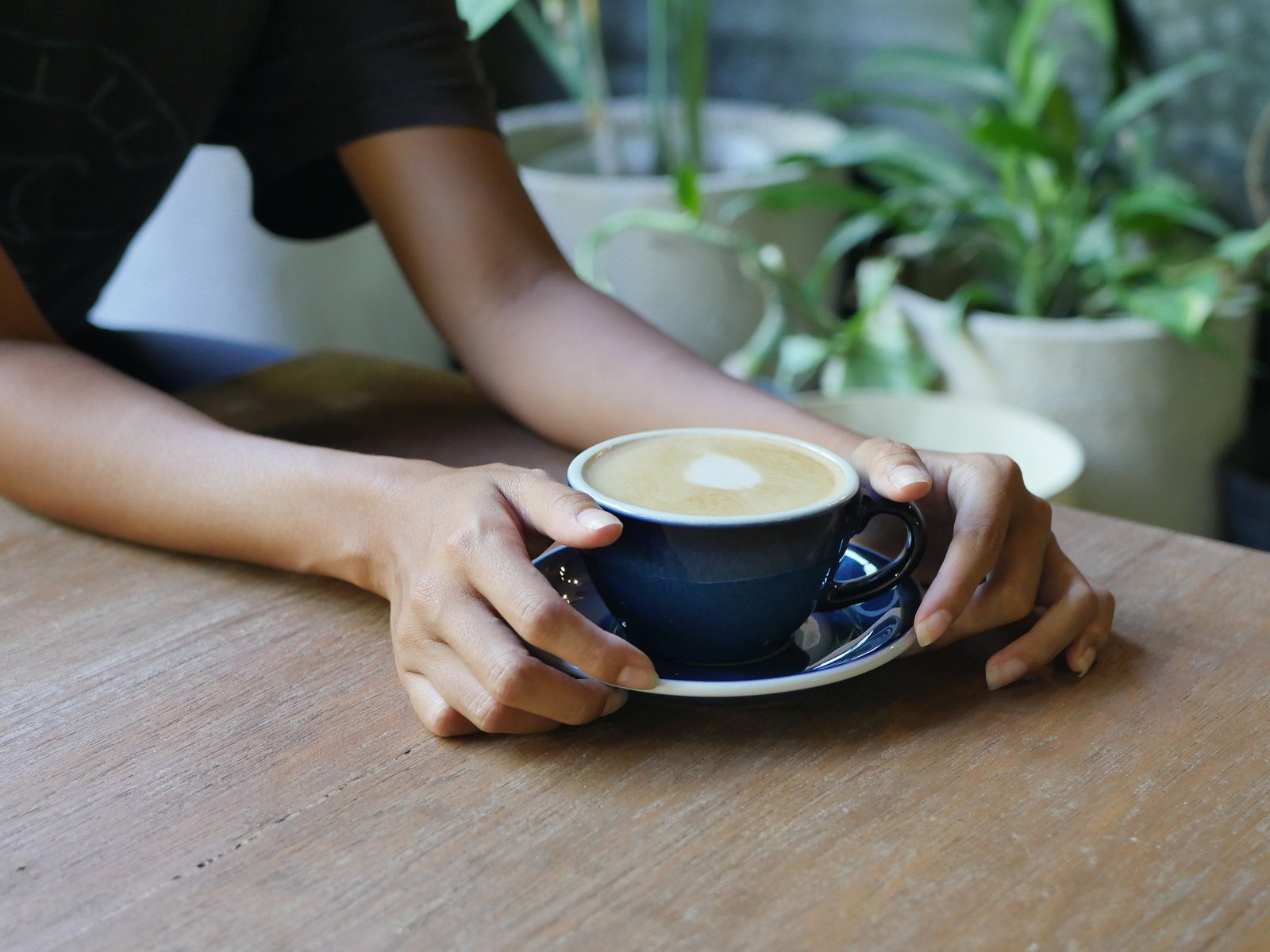 Hands holding a fresh latte at Vultun Wellness Cafe, Siargao
