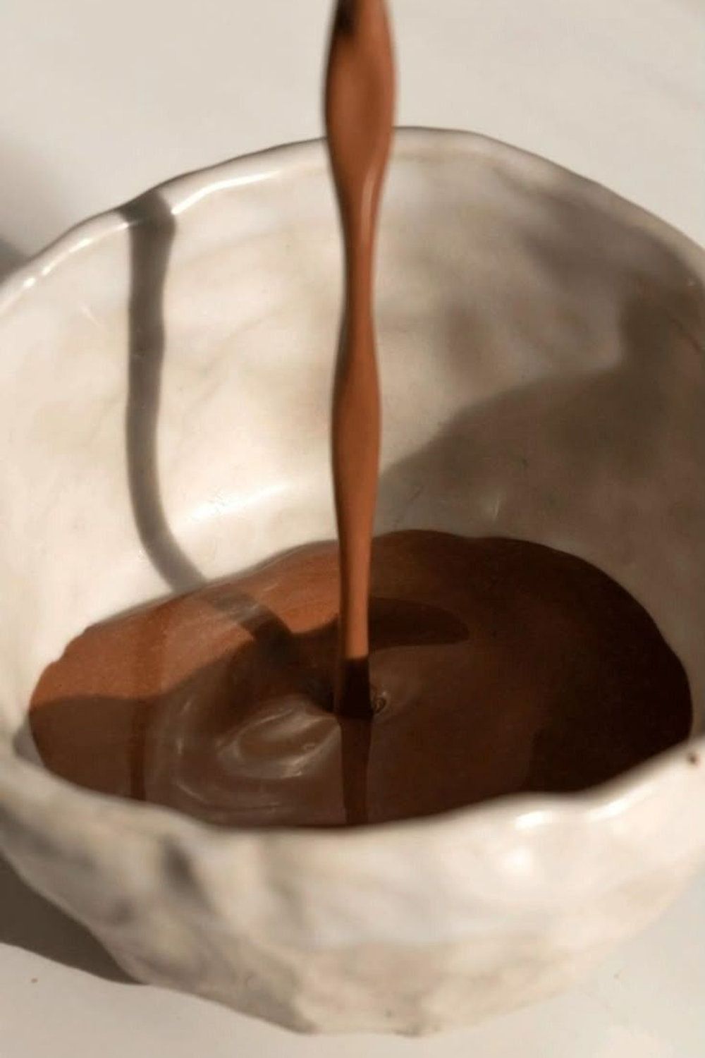 Ceremonial cacao being poured into handmade ceramic bowl