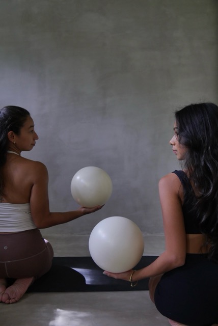 Two women seated with pilates barre balls at Feral Pilates Siargao