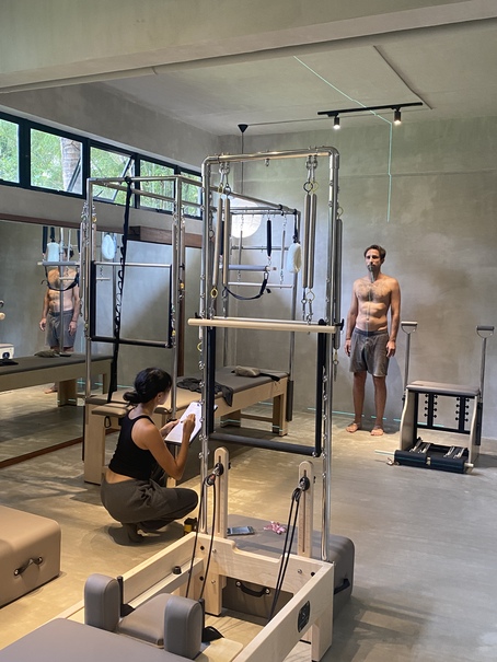 Allegra assessing a client beside the Cadillac reformer at Feral Pilates studio