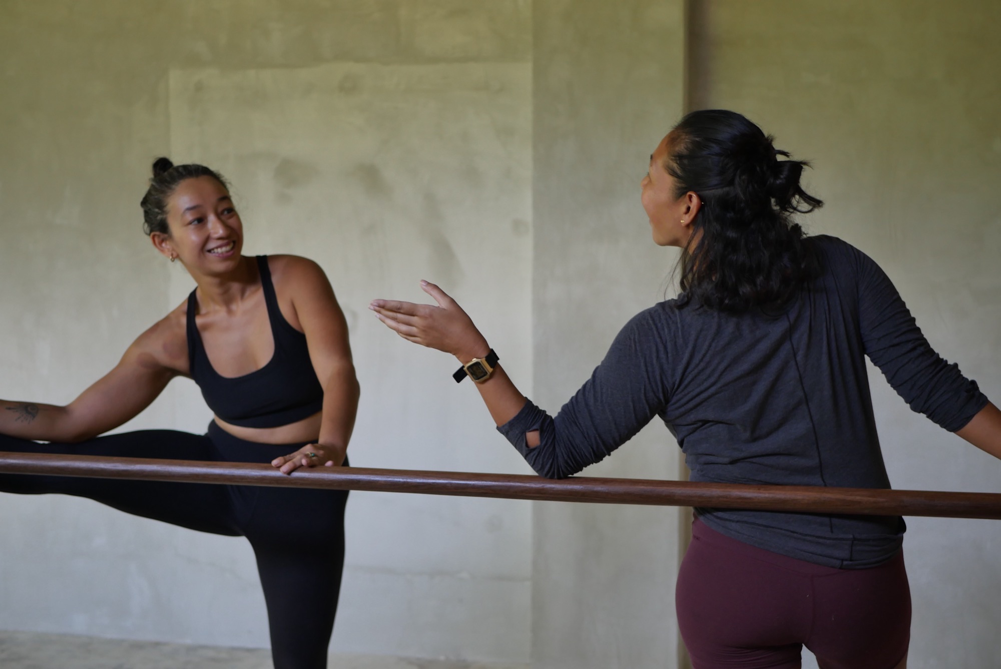Two instructors laughing and connecting at the barre during class at Feral Movement Siargao