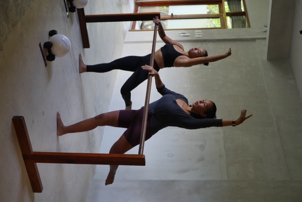 Two women performing barre leg extensions at Feral Movement Siargao